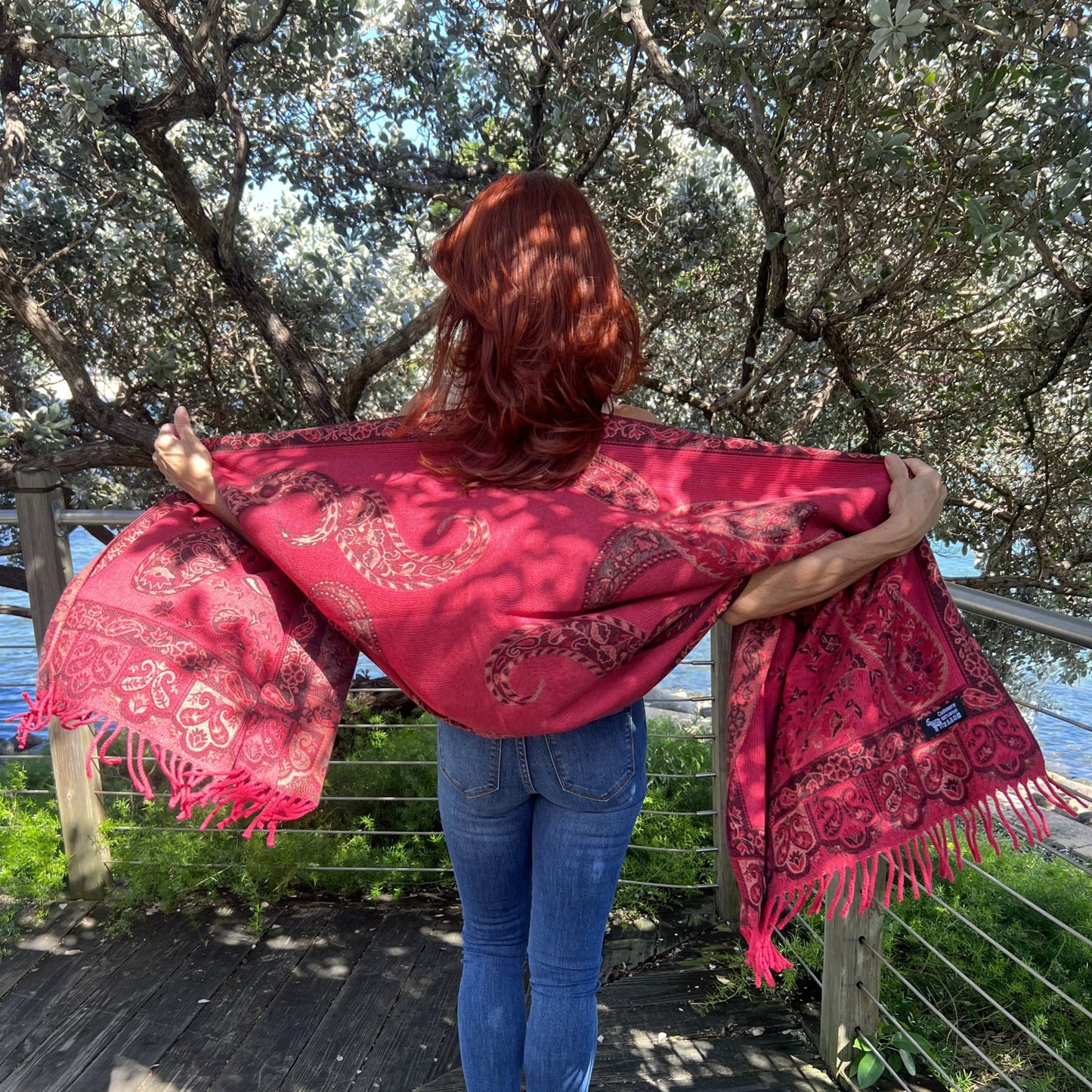 Mujer de Espaldas Mostrando Elegante Pashmina Roja con Estampado de Paisley y Flores/Pololena & Co.