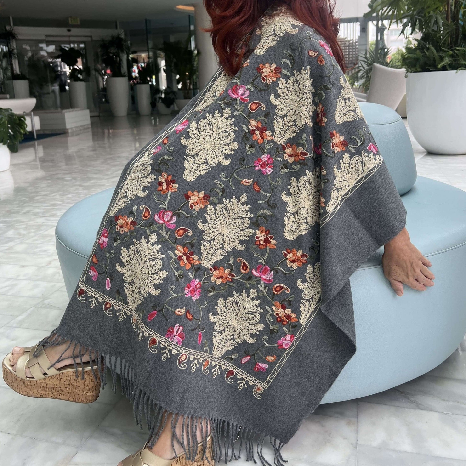 Mujer Sentada en Lobby de Hotel Cubre sus Hombros del Frío con una Pashmina Shawl en Embroidery/Pololena & Co.