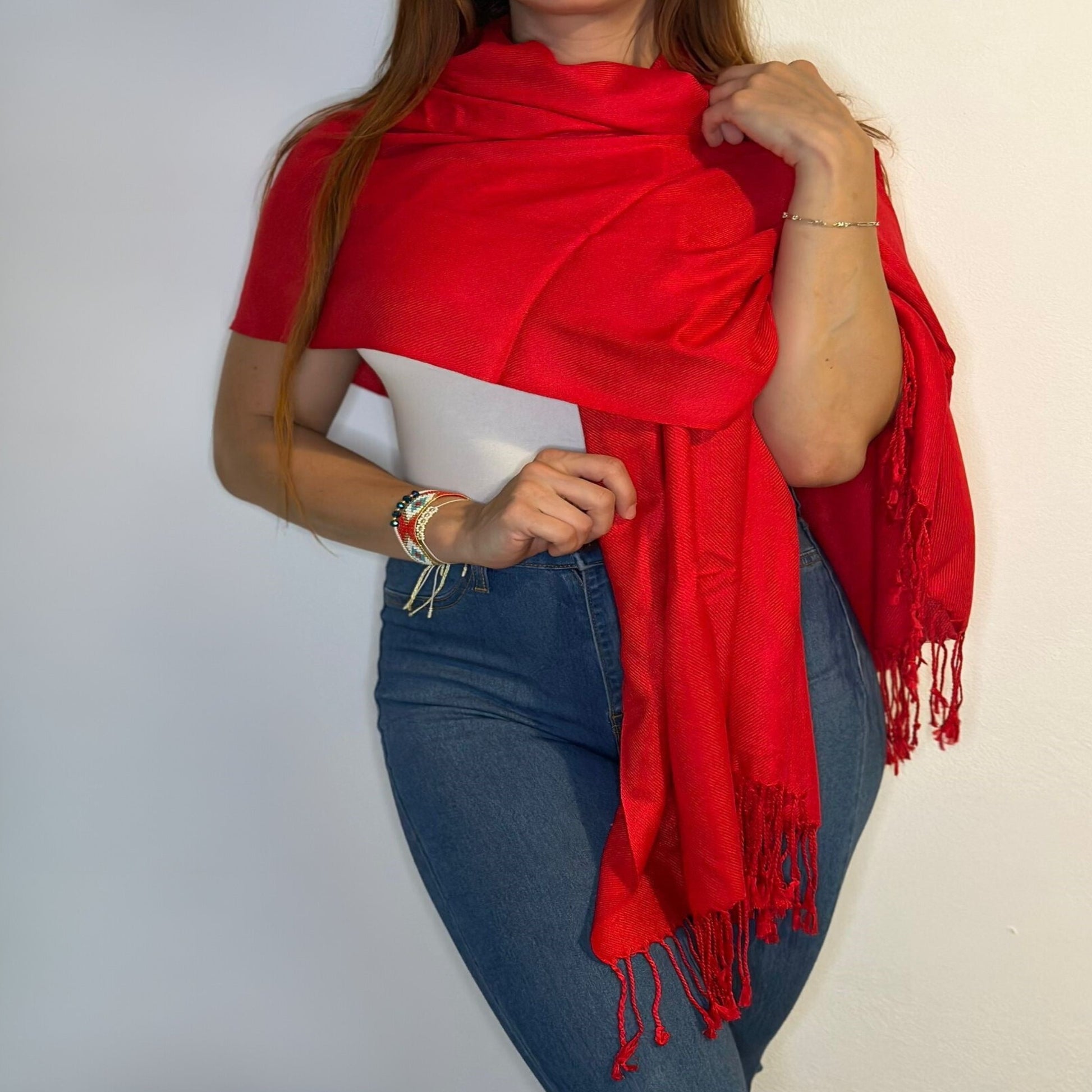 Mujer a Medio Cuerpo Mostrando Cómo Cubrir sus Hombros Elegantemente con una Pashmina Shawl Roja/Pololena & Co.